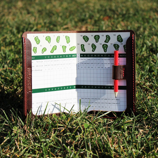 Scorecard holder with golf scorecard and pencil on grass