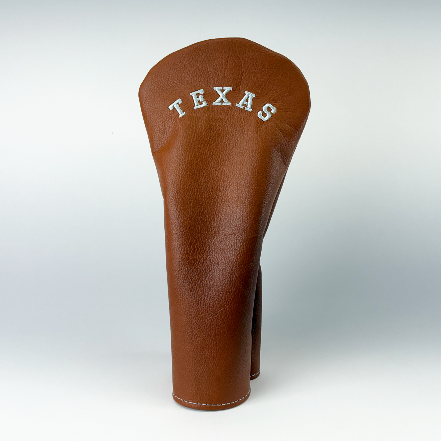 Brown leather headcover with 'TEXAS' embossed on a white background
