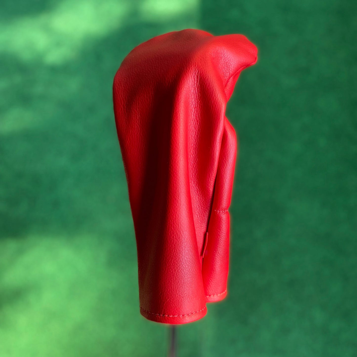 Red golf club head cover on a green background