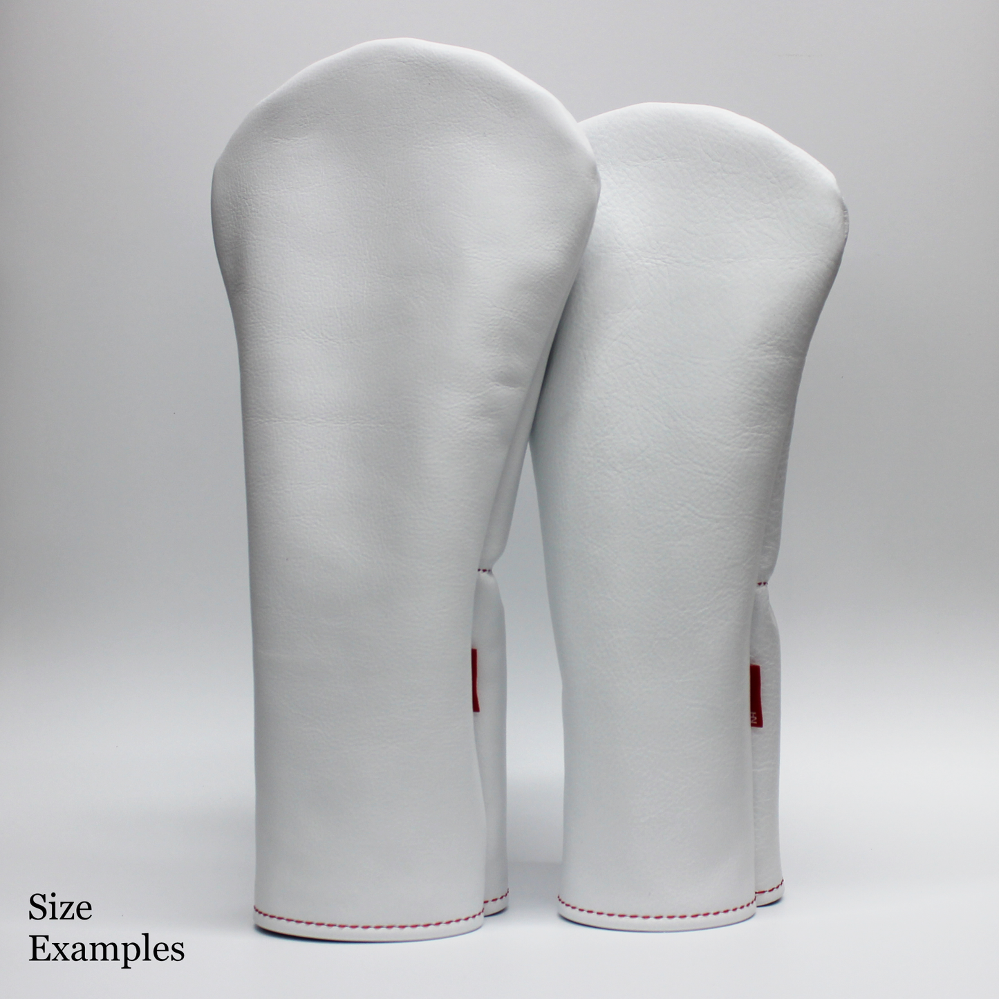 White golf club head covers with red accents on a gray background