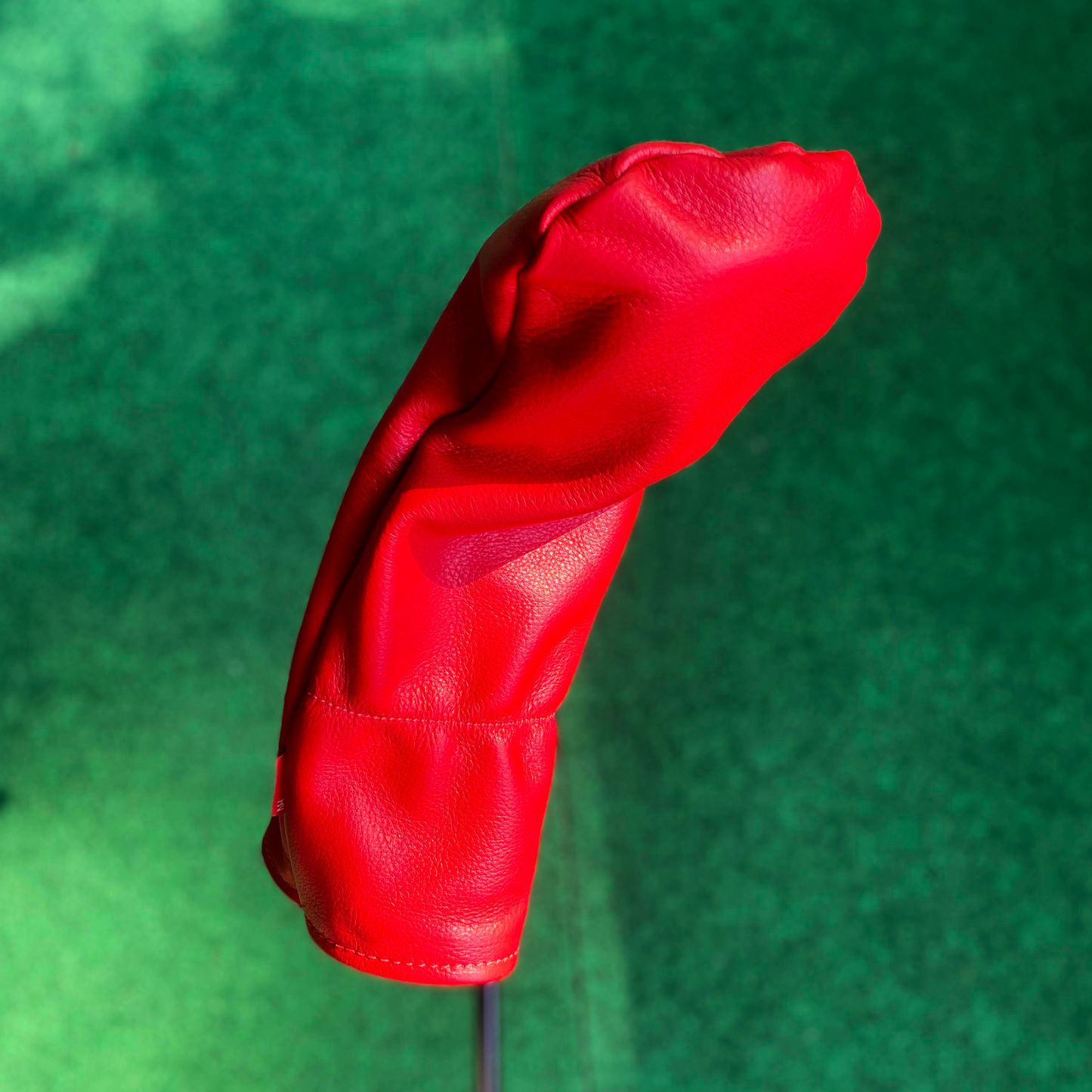 Red golf club head cover on a green background
