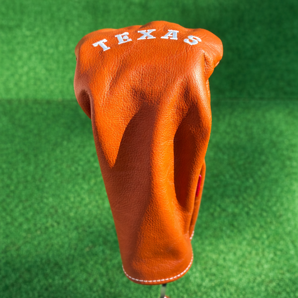 Orange golf club head cover with 'TEXAS' text on a green background