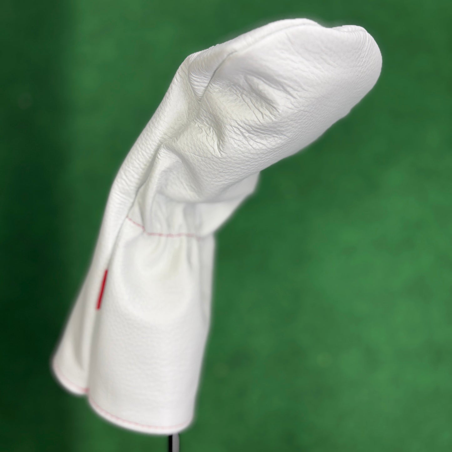White golf club head cover on a green background