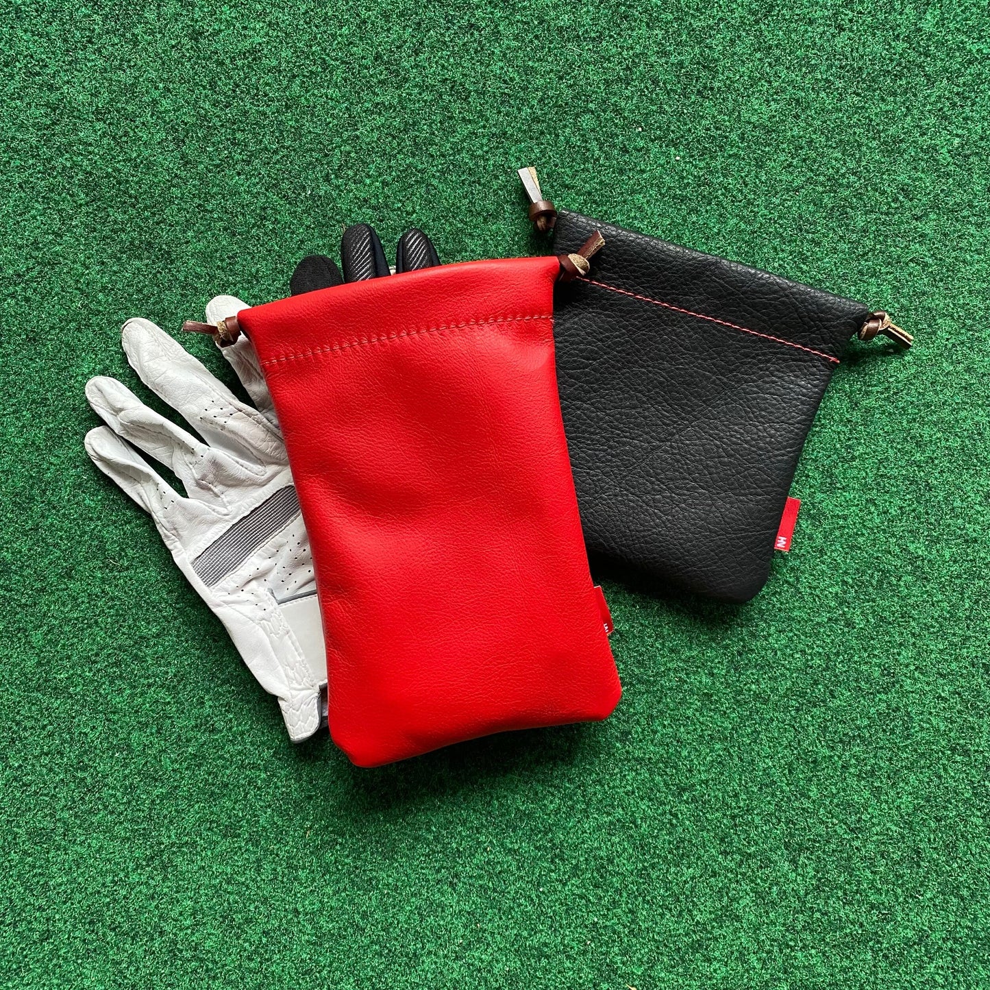 Red and black pouches with a white glove on a green surface