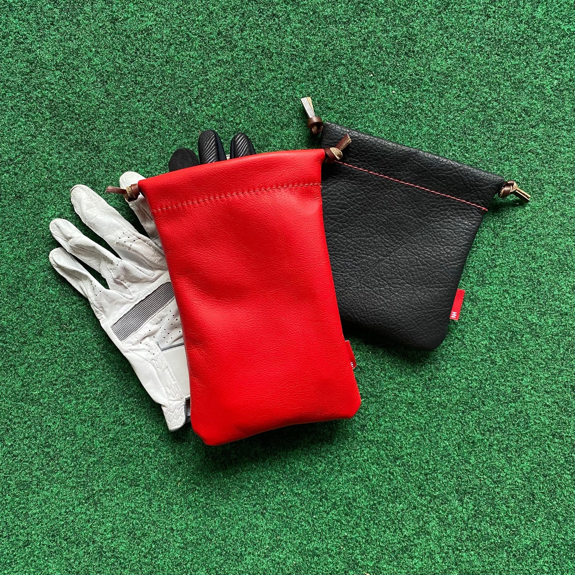 Red and black pouches with a white glove on a green surface