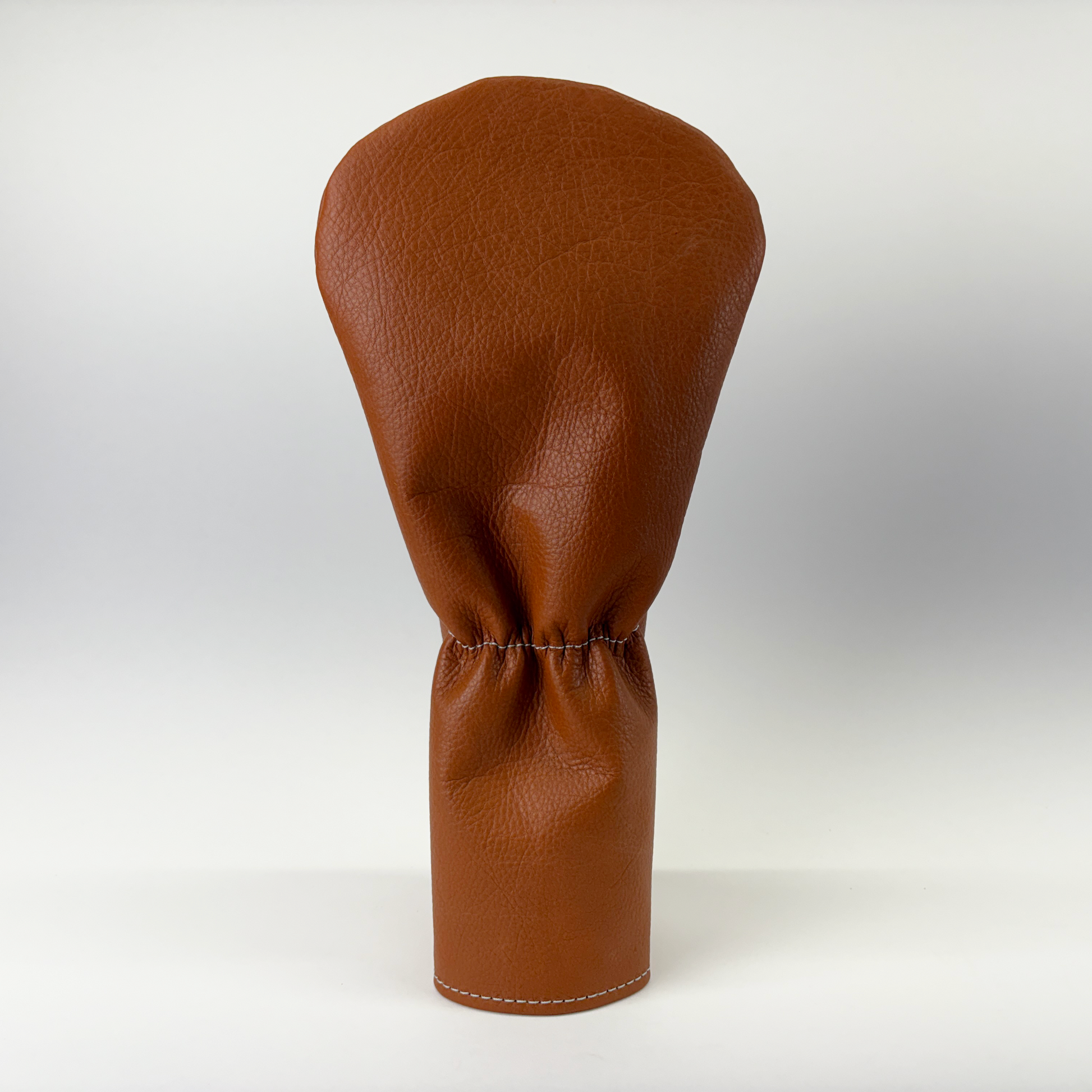 Brown leather golf club head cover on a white background