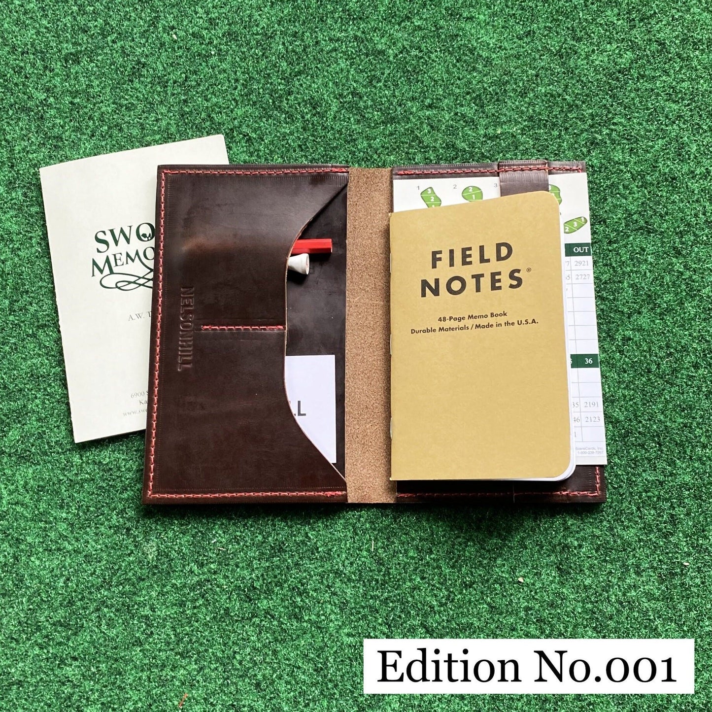 Edition number 001 leather notebook cover with 'Field Notes' notebook on a green textured background