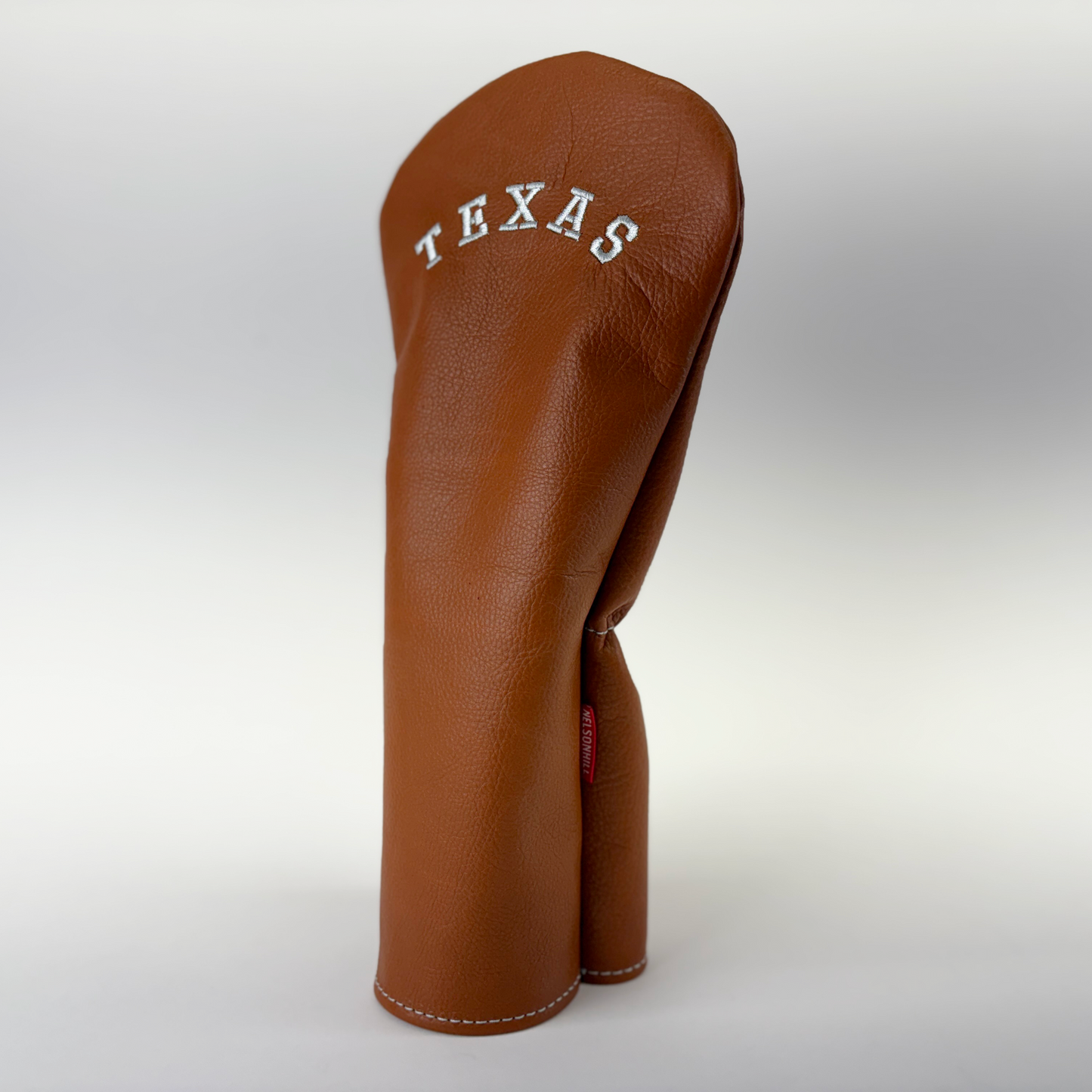 Brown leather golf club head cover with 'TEXAS' text on a white background