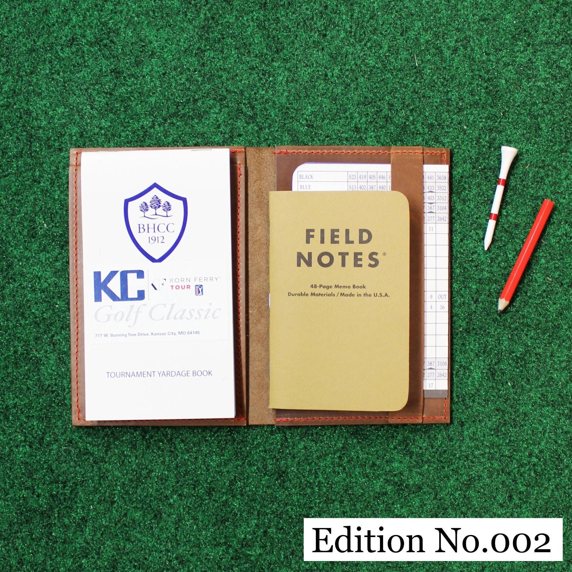 Edition number 002 leather notebook cover with 'Field Notes' notebook on a green textured background