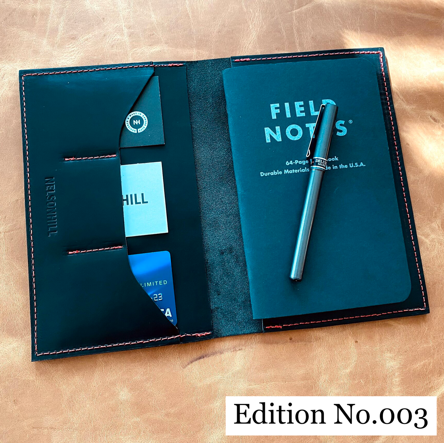 Edition number 003 leather notebook cover with 'Field Notes' notebook on a tan textured background