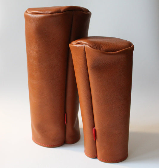 Two brown leather golf club covers on a white background