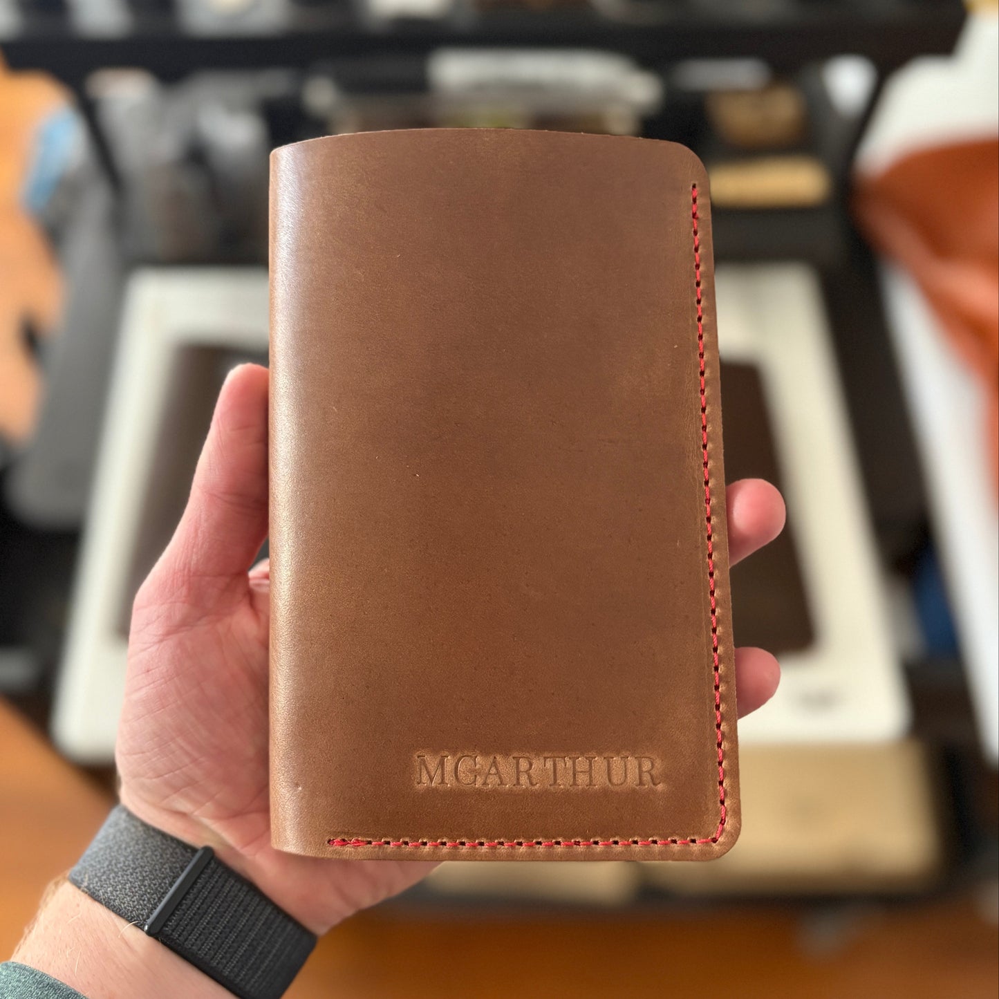 Natural leather scorecard wallet held in a hand with a blurred background