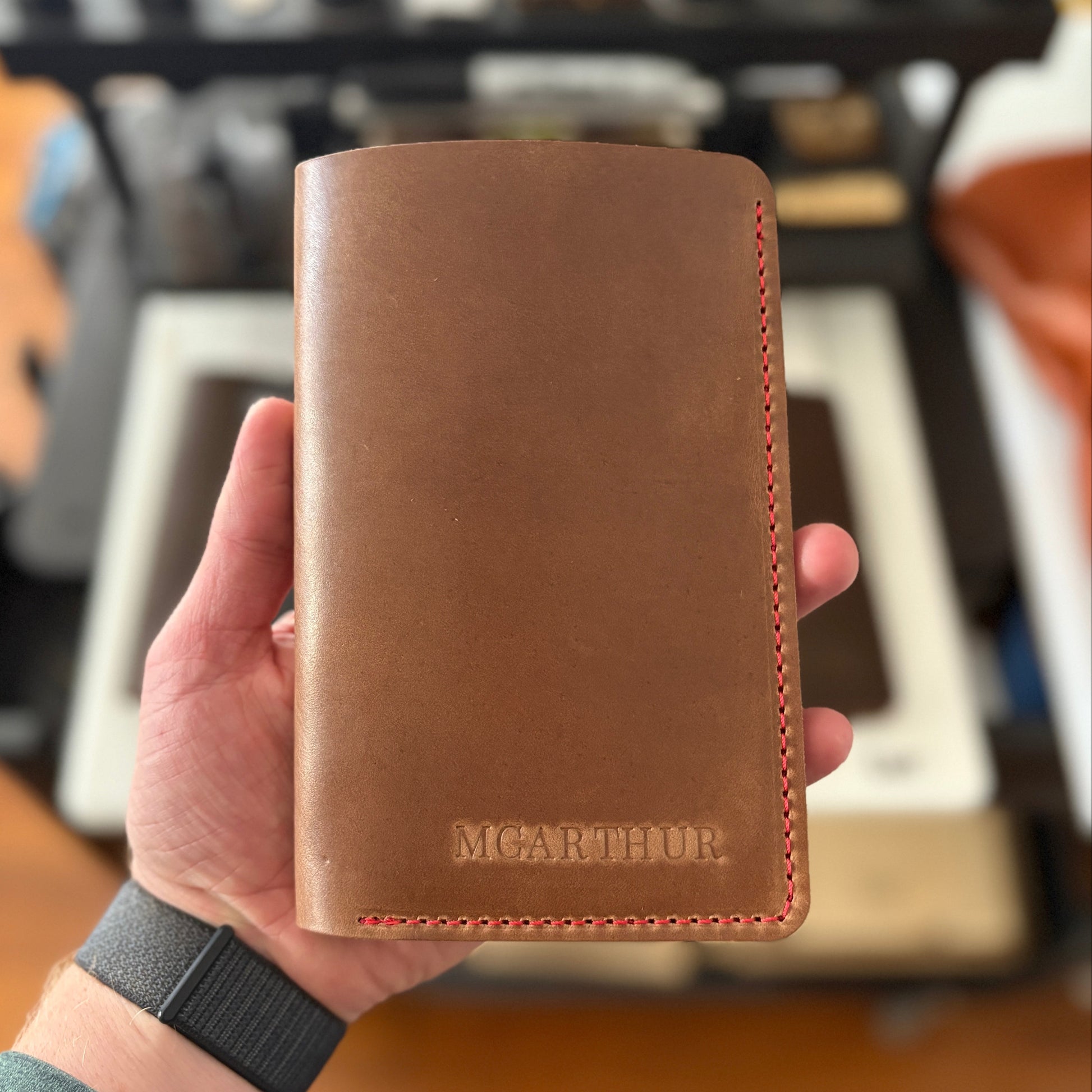 Natural leather scorecard wallet held in a hand with a blurred background